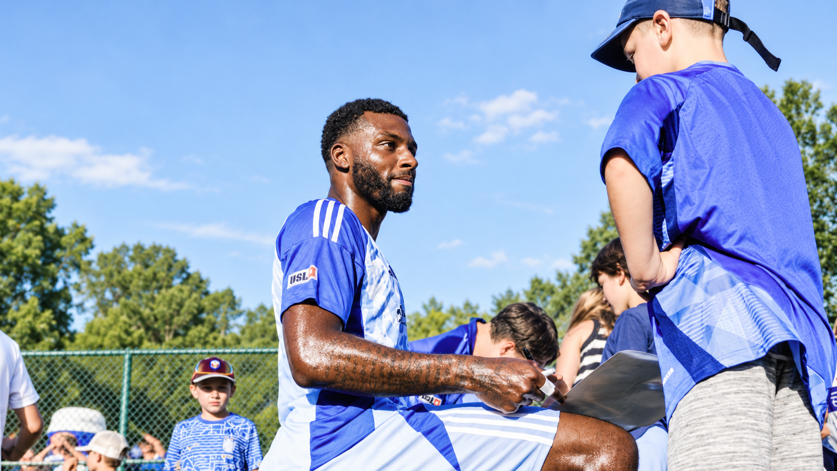 Charlottesville Blues FC first-team player connecting with young campers during a summer soccer camp.